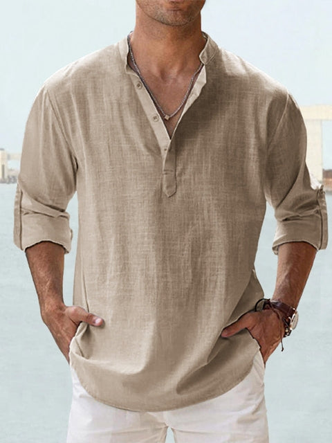 Homme portant une chemise en lin beige à col mao, manches retroussées, style décontracté, sur fond de plage. Mode estivale élégante pour homme.