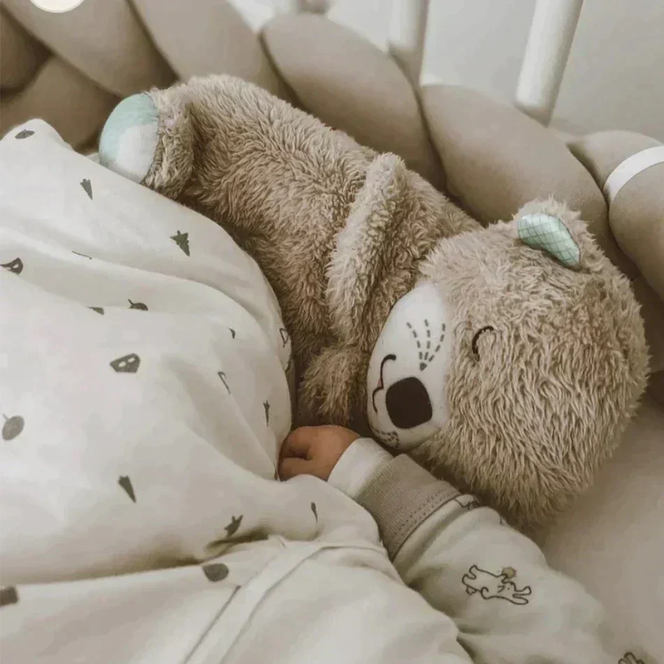 Kuscheltier Bär im Kinderbett, braun, Plüsch, neben schlafendem Baby, gemütlich, Babyzimmer.