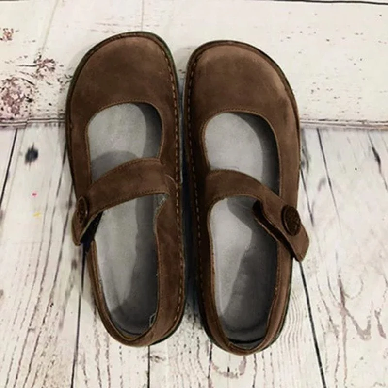 Chaussures Mary Jane marron en daim sur fond en bois clair, style vintage, confortables et élégantes, idéales pour un look rétro chic.