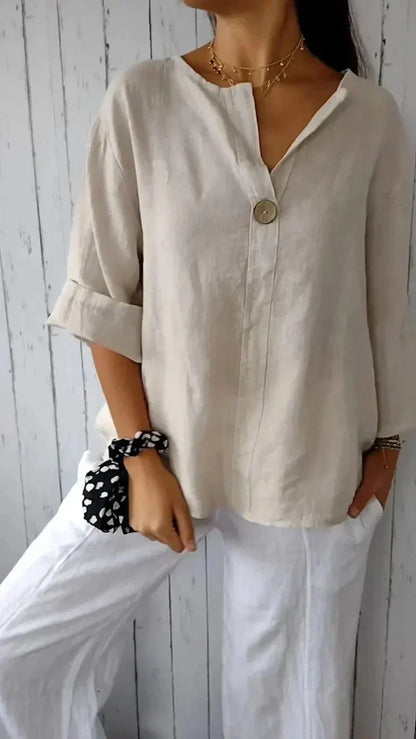 Femme portant une chemise en lin beige avec bouton, manches retroussées, associée à un pantalon blanc. Style décontracté, mode féminine élégante.