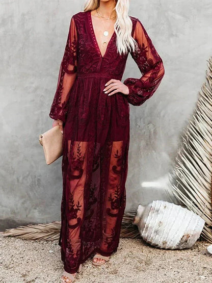 Robe longue en dentelle bordeaux transparente avec manches longues, tenue élégante pour soirée, femme tenant une pochette beige, fond neutre.