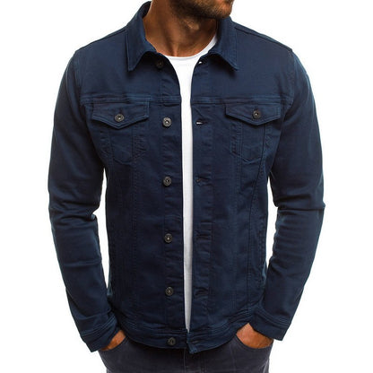 Veste en jean bleu marine pour homme, style décontracté, manches longues, boutons noirs, poches poitrine, portée sur un t-shirt blanc.
