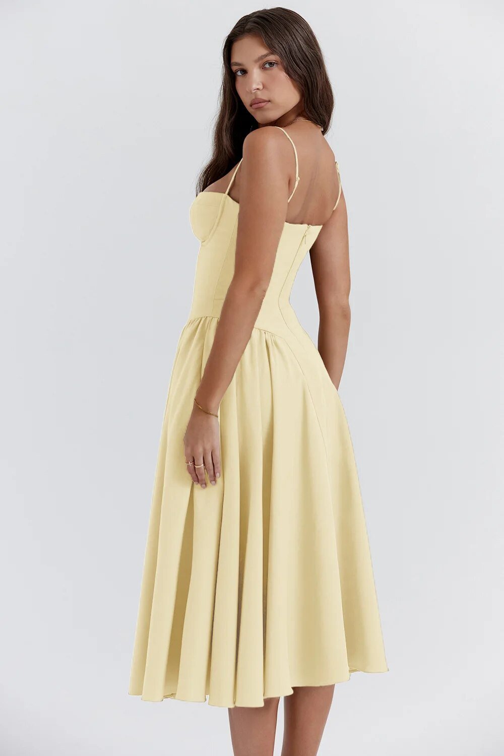 Robe midi jaune élégante, bretelles fines, coupe ajustée, jupe évasée, portée par une femme de dos. Mode féminine, tenue estivale chic.