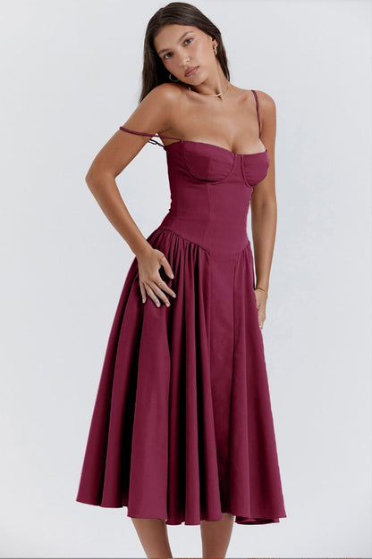 Robe midi bordeaux élégante avec bretelles fines, corsage ajusté et jupe évasée, portée par une femme. Mode féminine chic et tendance.