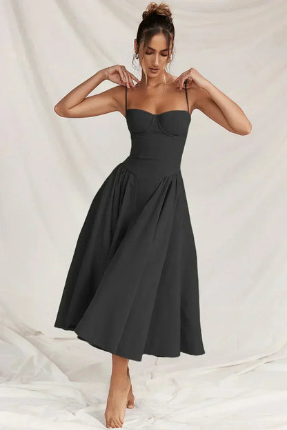 Robe noire élégante sans manches, longueur mi-mollet, portée par une femme sur fond neutre. Mode féminine chic, style classique intemporel.