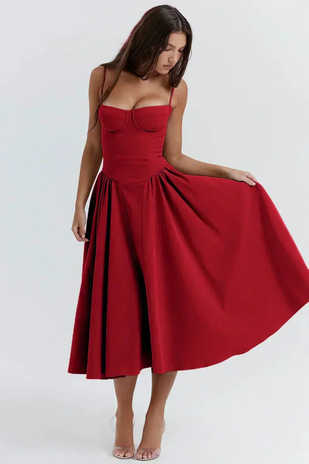 Robe rouge élégante, longueur mi-mollet, avec bretelles fines et corsage ajusté, portée par une femme. Mode féminine chic et tendance.