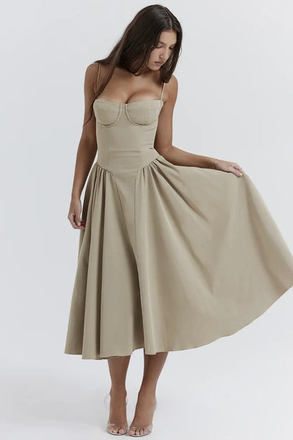 Femme portant une robe beige élégante, coupe évasée, bretelles fines, posant sur fond blanc. Mode féminine, tenue chic, style moderne.