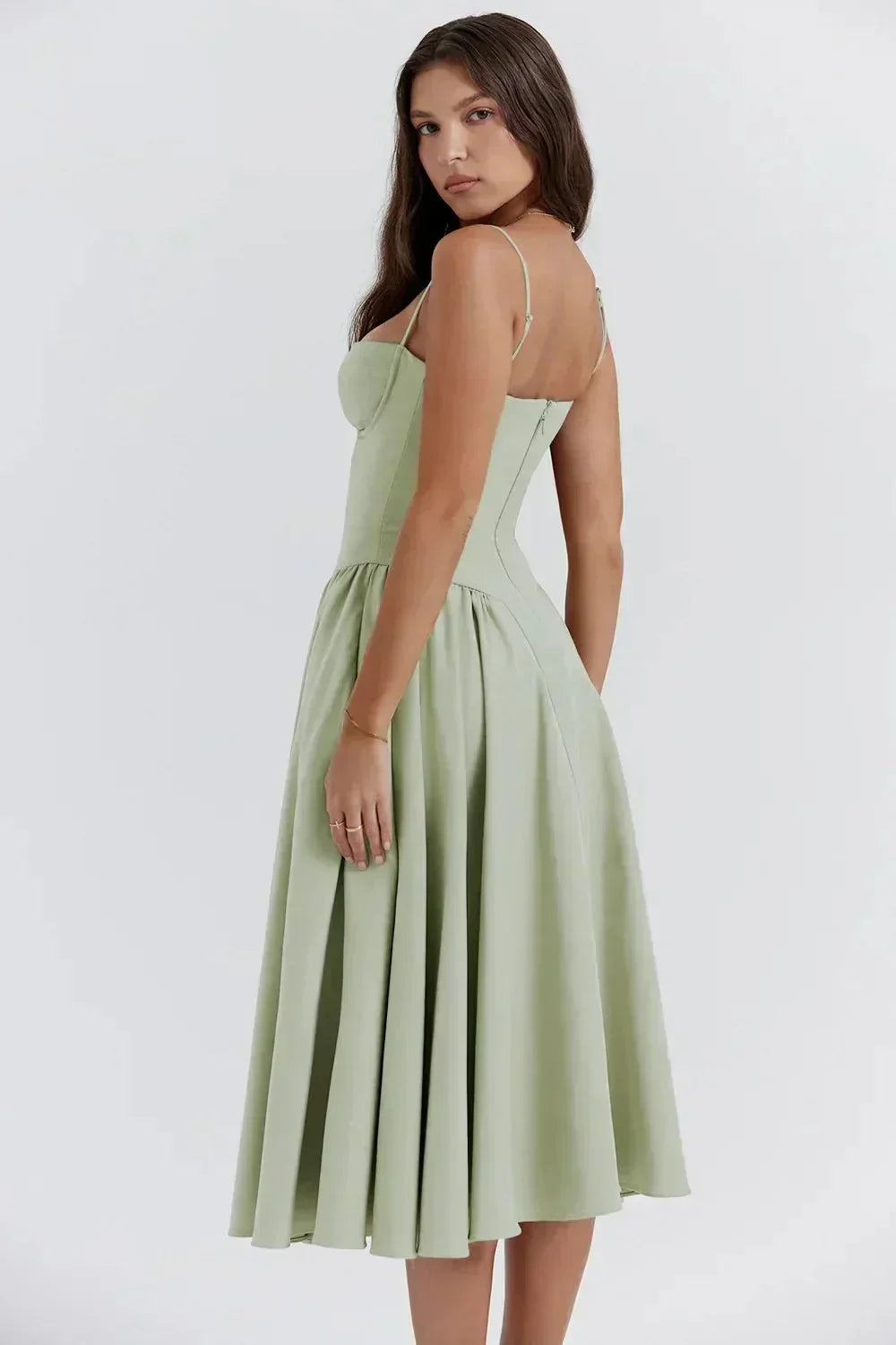 Robe midi verte élégante, bretelles fines, coupe ajustée, jupe évasée, femme de dos, mode féminine chic, style estival, tendance 2023.
